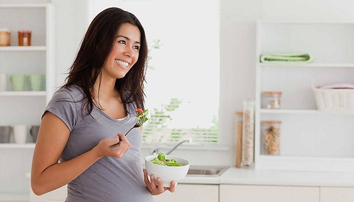 Pregnant girl eats vegetable salad