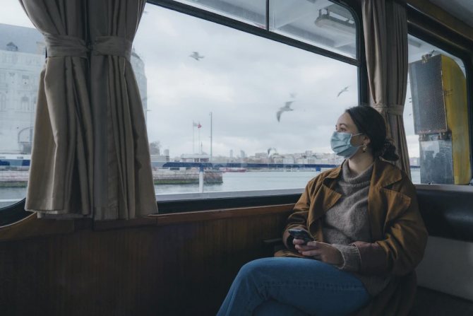 A woman wearing a protective mask looks out the window of a ferry in Turkey